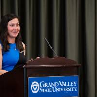 Woman in blue dress giving speech at podium